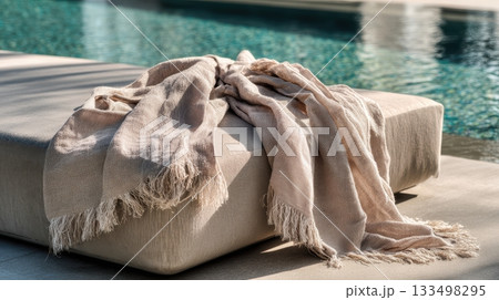 Soft blanket resting on a sunbed by a poolside Soft blanket resting on a sunbed by a poolside 133498295