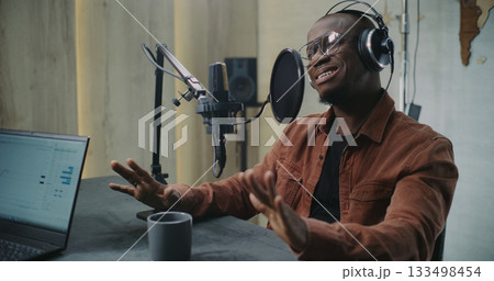 Adult Man Speaks Into Professional Studio Mic With Pop Filter, Wearing Headphones 133498454