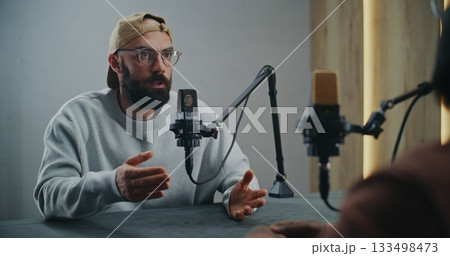 Bearded Podcast Host Leading Engaging Conversation in Studio Setting 133498473