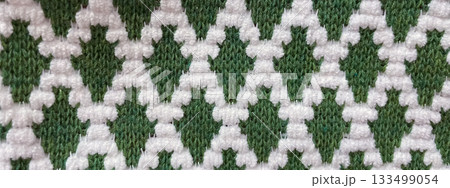 Macro texture background of green and white knitted fabric with a distinct geometric diamond pattern 133499054