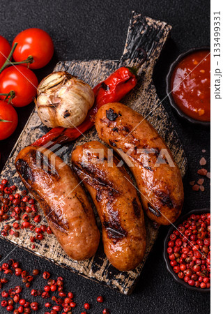 Grilled chicken or beef sausages with sauce and spices. Grilled sausages 133499331