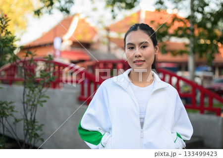 Young Asian Woman in Sporty Casual Outfit Outdoors in Traditional Garden Young Asian Woman in Sporty Casual Outfit Outdoors in Traditional Garden 133499423