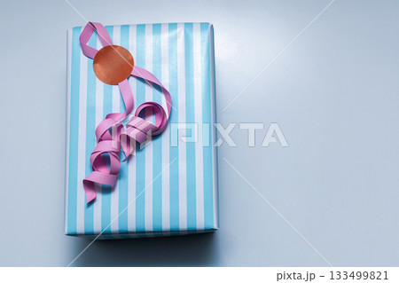 Blue and white striped present on pastel background Blue and white striped present on pastel background 133499821