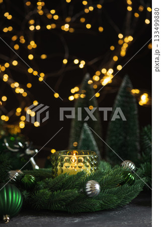 Lit Candle in Green Glass Holder with Pine Wreath and Christmas Ornaments Lit Candle in Green Glass Holder with Pine Wreath and Christmas Ornaments 133499880