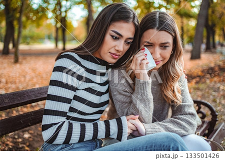 Friends enjoy a heartfelt moment in a golden autumn park 133501426