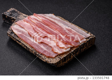 Raw or smoked pork bacon slices or strips as a breakfast ingredient. Raw bacon Raw or smoked pork bacon slices or strips as a breakfast ingredient. Raw bacon 133501748