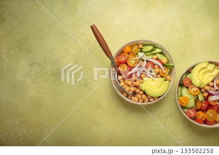 Two bowls with vibrant vegetarian chickpea salad with fresh vegetables in ceramic bowls top view on light green background, space for text Two bowls with vibrant vegetarian chickpea salad with fresh vegetables in ceramic bowls top view on light green background, space for text 133502258