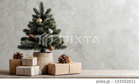 Rustic christmas tree with pine cones and gift boxes on wooden table against neutral background 133502611