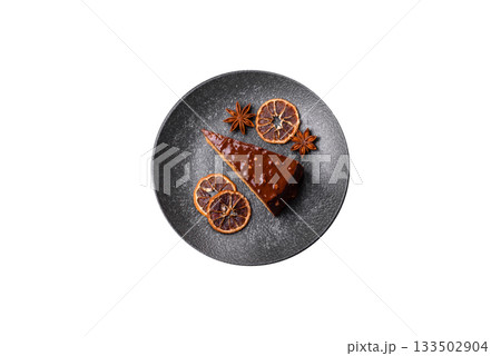 A slice of sweet layered cake covered in chocolate with nuts and caramel. A slice of chocolate cake 133502904