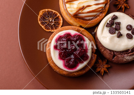 Cinnamon roll, a sweet bun with citrus, cherries, and chocolate, a Danish dessert with cream 133503141