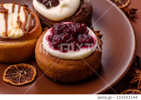 Cinnamon roll, a sweet bun with citrus, cherries, and chocolate, a Danish dessert with cream 133503144