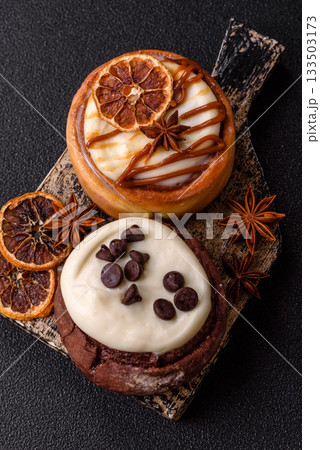 Cinnamon roll, a sweet bun with citrus, cherries, and chocolate, a Danish dessert with cream 133503173