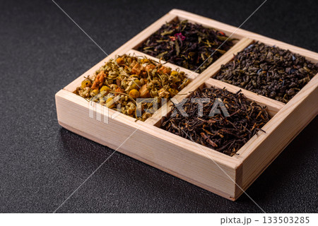 A wooden box with several types of dried tea, green, black, fruit, and chamomile. Dry tea in the box 133503285