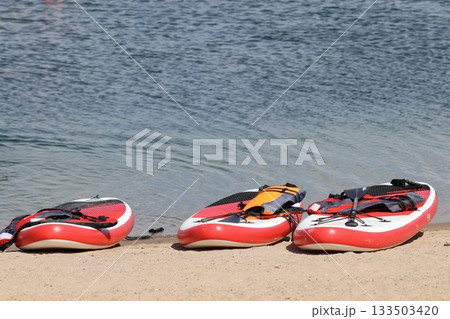 Three SUP boards on a sandy beach near the water 133503420