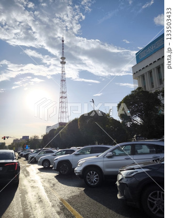 The Koktobe TV tower against the backdrop of a city street with parked cars in Almaty. 133503433