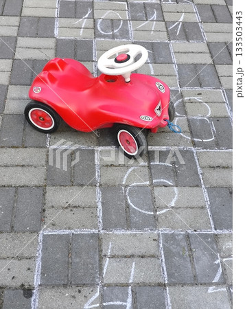 Bright childhood: a red car and hopscotch on the asphalt Bright childhood: a red car and hopscotch on the asphalt 133503443
