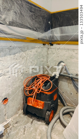 Cleaning after removing plaster to combat mold in the corner of a room with a professional vacuum cleaner Cleaning after removing plaster to combat mold in the corner of a room with a professional vacuum cleaner 133503494