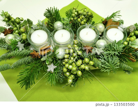 Advent wreath or tabletop arrangement with four white candles and green branches Advent wreath or tabletop arrangement with four white candles and green branches 133503500