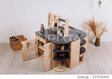 Wooden kids play kitchen island with shelves in minimalist nursery interior 133504495