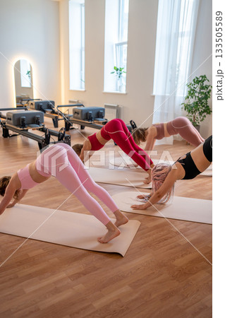 Group synchronized downward dog practice on mats with instructor guidance and flowing transitions 133505589