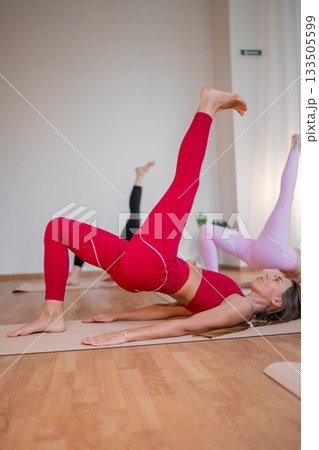 Pilates women performing inverted leg raises, pair of women practicing inverted leg raises with focus on the buttocks Pilates women performing inverted leg raises, pair of women practicing inverted leg raises with focus on the buttocks 133505599