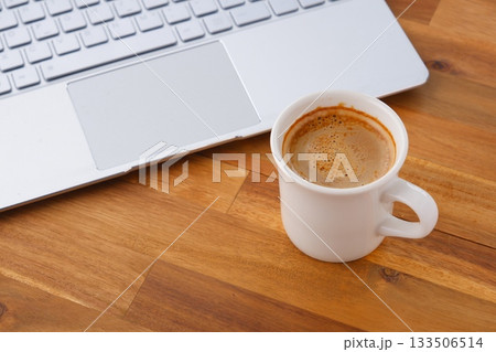 パソコンとコーヒー - 淹れたてのコーヒーを飲みながら、ノートパソコンでデスクワーク中のイメージ 133506514
