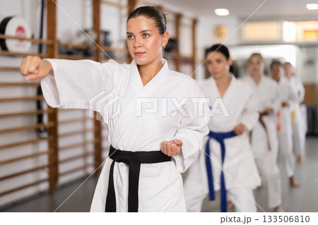 Young woman practicing punches standing in row with others Young woman practicing punches standing in row with others 133506810