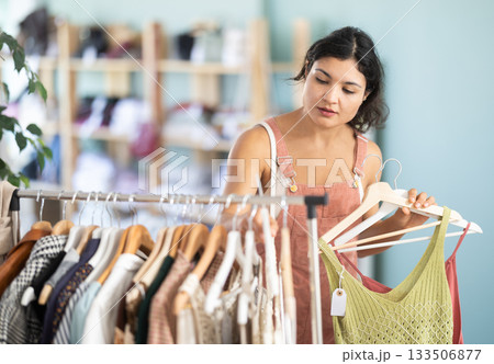 Woman chooses dresses or o tops for the summer period in fashionable clothing store Woman chooses dresses or o tops for the summer period in fashionable clothing store 133506877