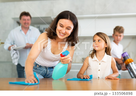 Positive mother and daughter cleaning the surface of kitchen table Positive mother and daughter cleaning the surface of kitchen table 133506898