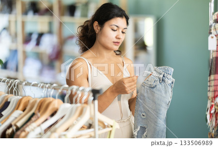 Undetermined young girl choosing jeans pantaloons in clothing store 133506989