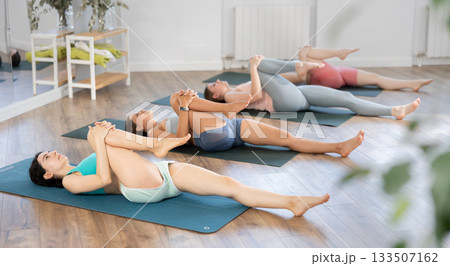 Young girl performing Eka Pada Apanasana in yoga studio 133507162