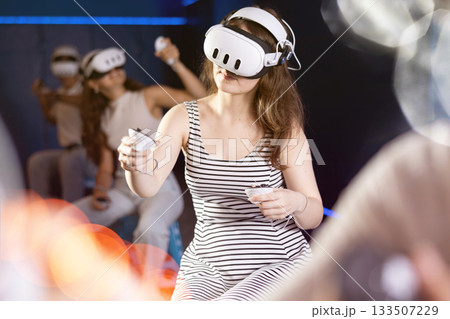 Expressive girl in VR goggles having fun in virtual reality room 133507229