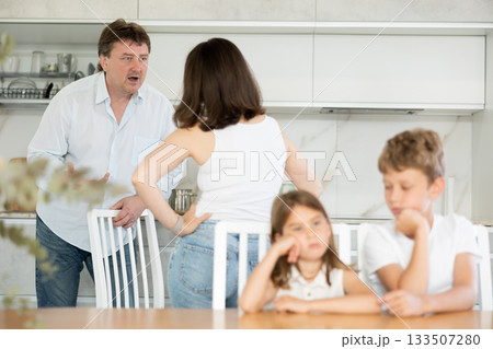 Family problem, conflict and people concept - sad children sitting at table their parents quarreling at home 133507280