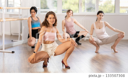 Women wearing casual activewear performing sensual and modern high heels choreography during group class in studio 133507308