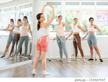 Young female ballet student performing solo during group practice 133507347