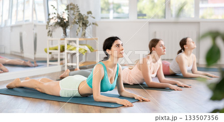 Young girl maintaining Sphinx Pose on mat during group yoga workout Young girl maintaining Sphinx Pose on mat during group yoga workout 133507356