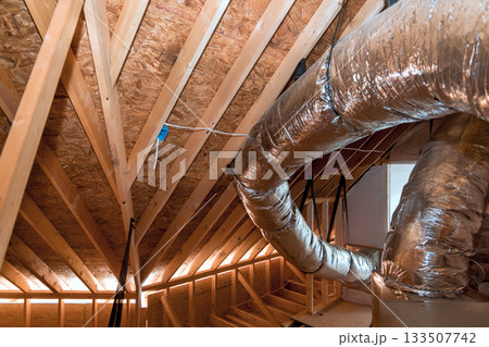 Attic features wooden rafters shiny ductwork, construction insulation 133507742