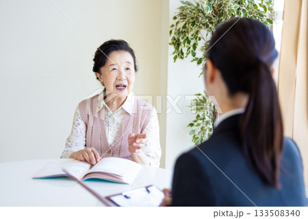 終活　エンディングノートに記入するシニア女性と相談員 133508340