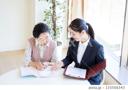 終活 エンディングノートに記入するシニア女性と相談員 終活 エンディングノートに記入するシニア女性と相談員 133508343