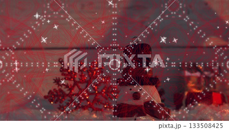 Displaying snowman figurine wearing black top hat, red scarf at home, with red snowflake ornament 133508425