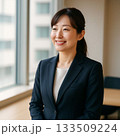 窓際で微笑む女性ビジネスパーソン（Businesswoman Smiling by the Wind 133509224