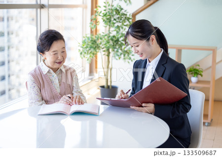 終活 エンディングノートに記入するシニア女性と相談員 終活 エンディングノートに記入するシニア女性と相談員 133509687