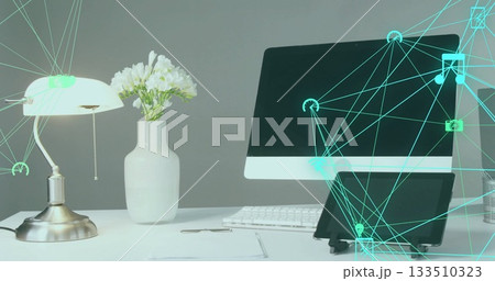 Showing monitor above keyboard on office desk, metallic pull-chain lamp, tablet and digital overlay 133510323