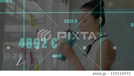 Asian woman in blouse holding mug analyzing currency figures on sticky notes in office, copy space Asian woman in blouse holding mug analyzing currency figures on sticky notes in office, copy space 133510472