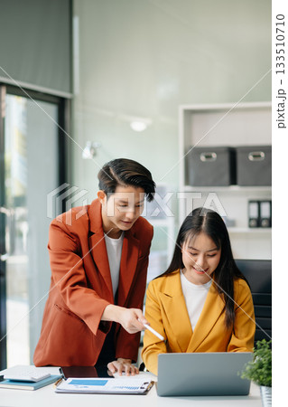 Businesswomen work and discuss their business plans. A Human employee explains and shows her colleague the results paper Businesswomen work and discuss their business plans. A Human employee explains and shows her colleague the results paper 133510710