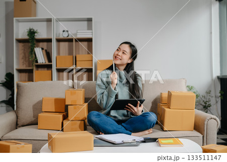 woman using smartphone or tablet taking receive and checking online purchase shopping order to preparing pack product box. 133511147