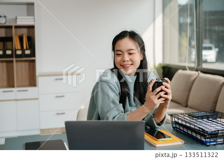 Asian businesswoman working with working notepad, tablet and laptop documents talking on the smartphone, tablet and laptop video call tax, report, accounting 133511322