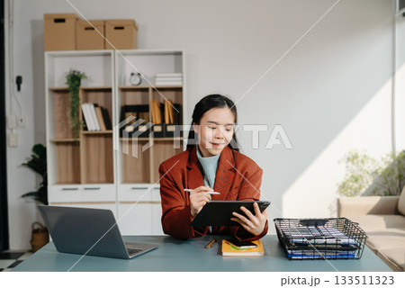 Asian businesswoman working with working notepad, tablet and laptop documents talking on the smartphone, tablet and laptop video call tax, report, accounting Asian businesswoman working with working notepad, tablet and laptop documents talking on the smartphone, tablet and laptop video call tax, report, accounting 133511323