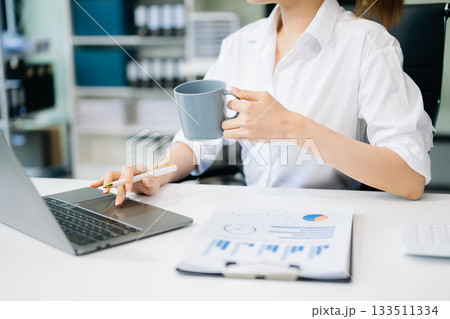 Asian woman with a smile standing holding notepad and tablet at the office. Asian woman with a smile standing holding notepad and tablet at the office. 133511334