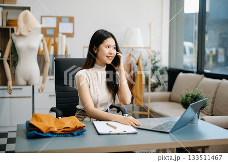 fashion designer. Attractive woman with smile while standing in workshop. Beautiful owner woman working fashion designer. Attractive woman with smile while standing in workshop. Beautiful owner woman working 133511467
